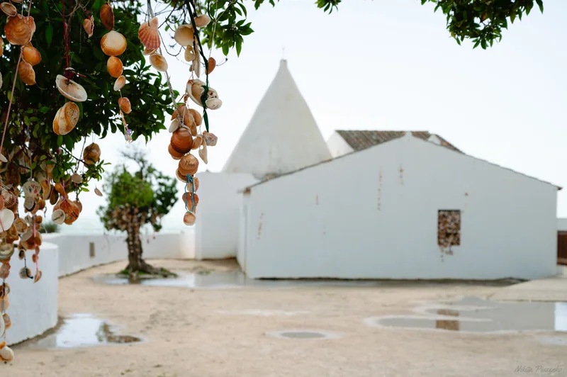 A white Portuguese chapel is framed by leaves and hanging ornaments.