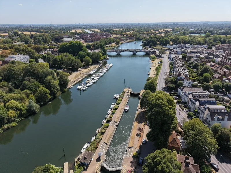 Aerial view along a river with moored boats and a bridge