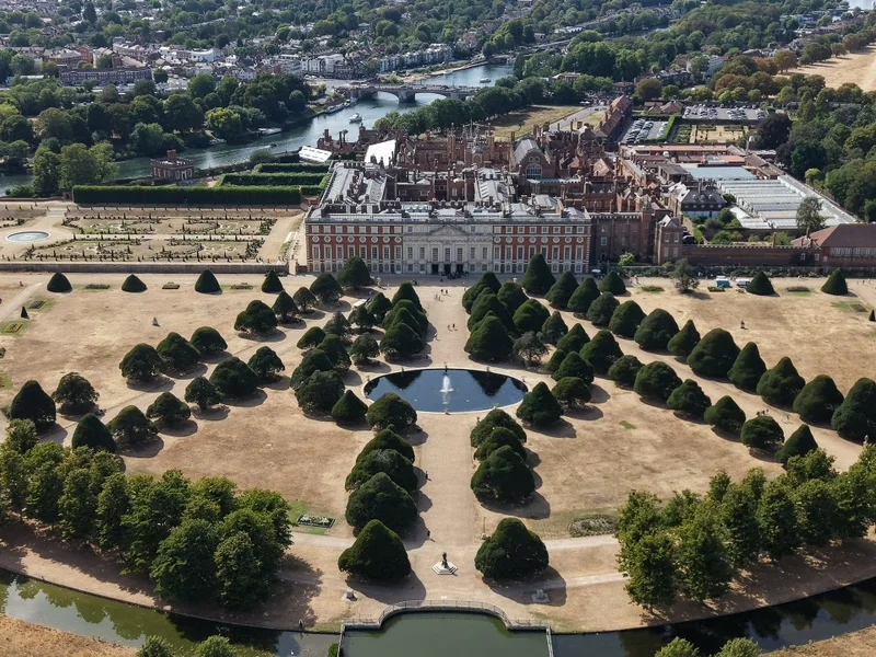 Aerial view of a palace and formal gardens beside a river