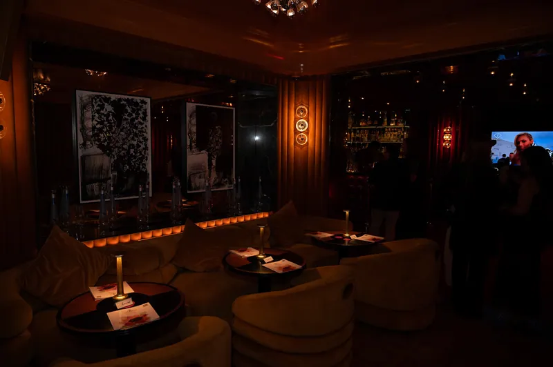 Amber-lit FashionTV lounge with artworks, guests and intimate table lighting