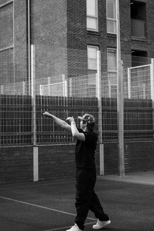 Black-and-white basketball shooting follow-through beside a fence