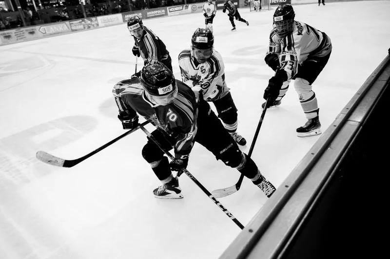 Black-and-white hockey challenge at close range beside the boards.