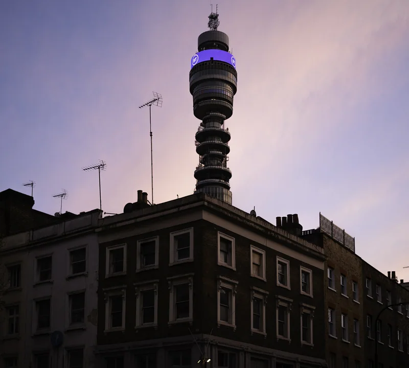 BT Tower rising above dark rooftops beneath a violet evening sky