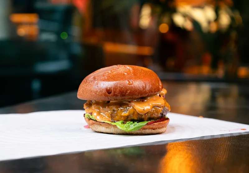 Burger on a white paper liner against a softly lit restaurant