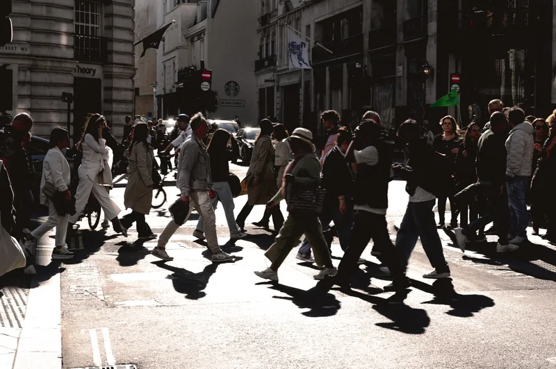 Crossing crowd caught in raking sun and long shadows
