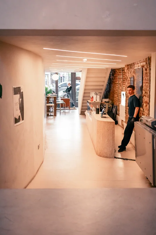 Curved white café interior with a barista behind the counter at COODIE