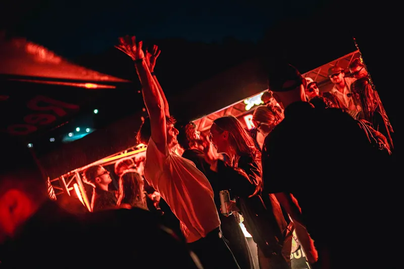 Dancer with raised arms beneath red lights at the District boat event in Vilnius