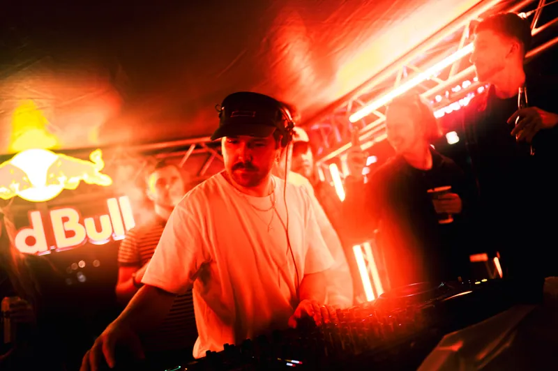 DJ performing under warm red light at the District boat event in Vilnius