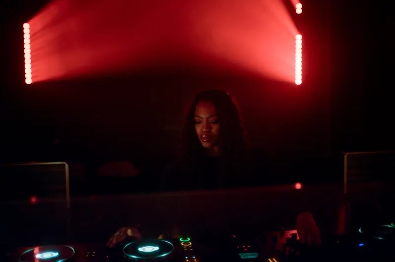 DJ framed by red stage lighting at 77 London