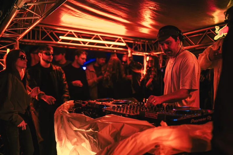 DJ playing beneath the red-lit canopy at District 29