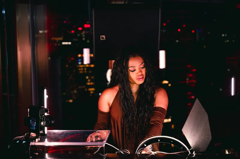 DJ working at the decks against the city lights at CE LA VI