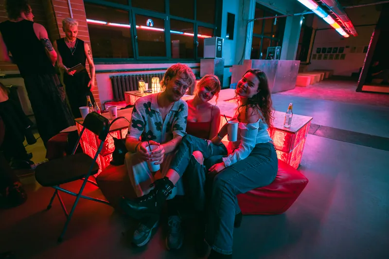 Three friends sharing a moment in the red seating area at Gallery 1986