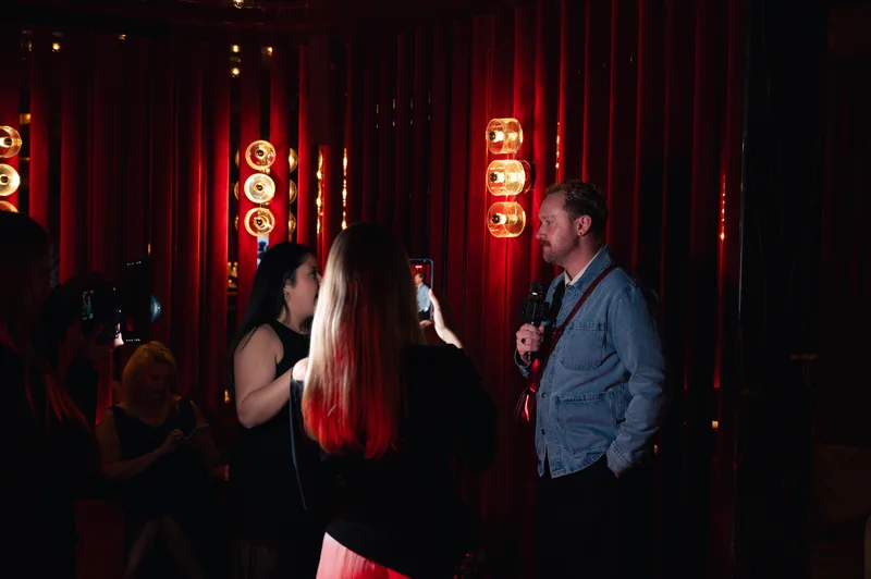 Guests talking beneath warm red lighting at FashionTV