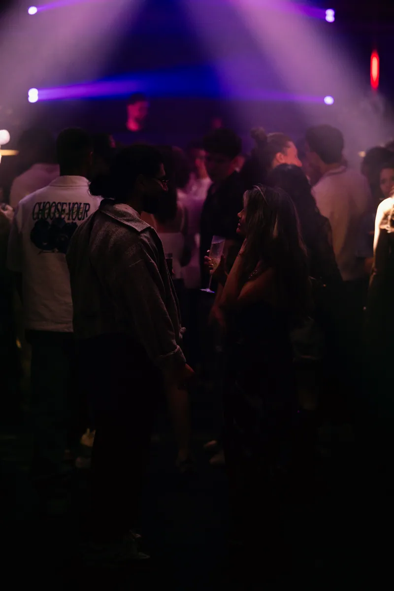 Guests talking on the dance floor under violet lights at 77 London