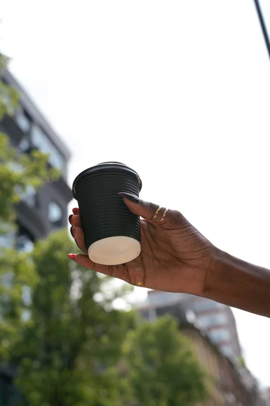 Hand holding a takeaway coffee against the Soho streetscape