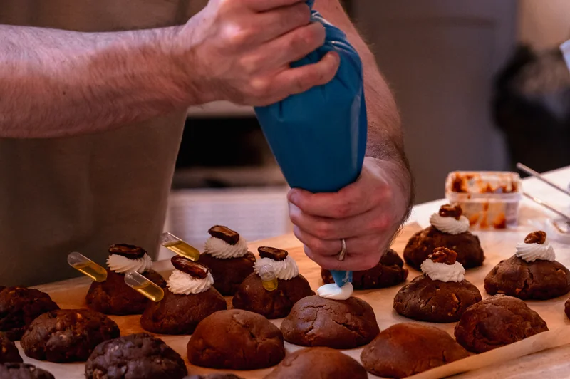 Hands piping icing onto pastries during the COODIE café session