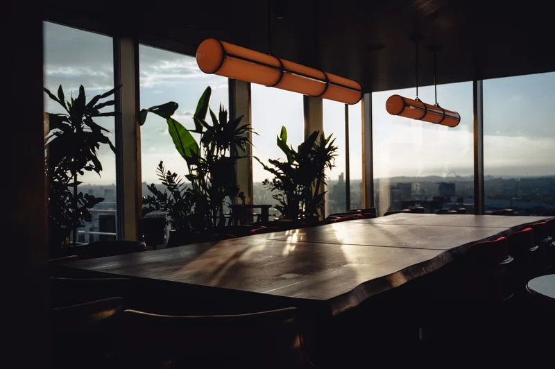 Late sunlight crosses an empty restaurant table beneath linear pendants.