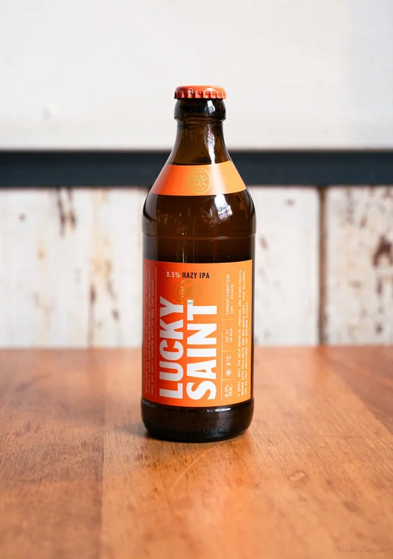 Lucky Saint bottle on a wooden tabletop with a clear orange label.