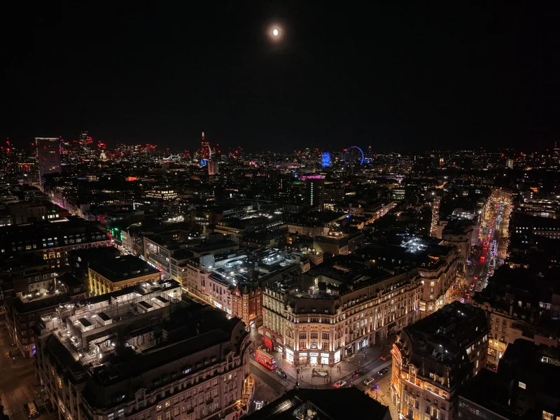 Moon above the London skyline and illuminated streets at night