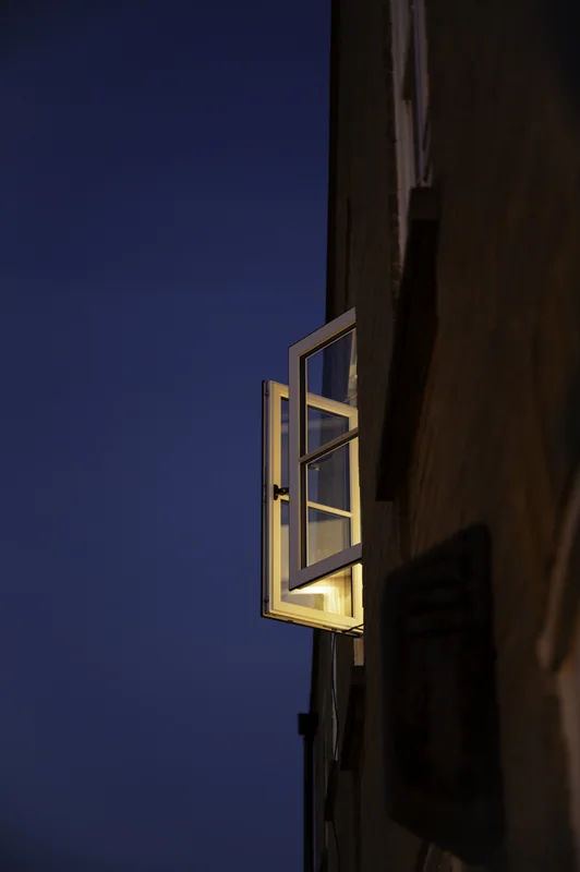 Open window projecting from a dark wall against a deep blue sky