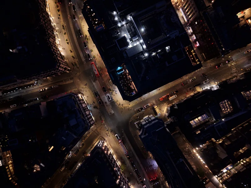 Overhead photograph of illuminated London streets and a rooftop terrace at night