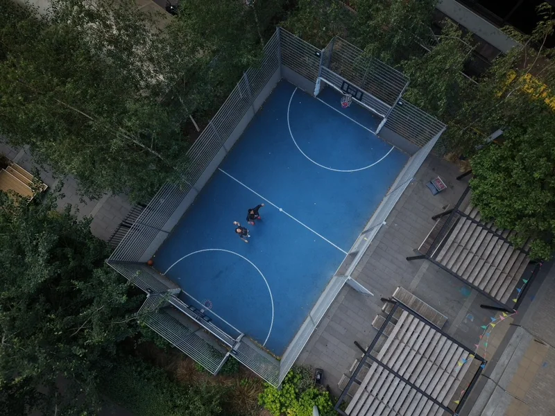 Overhead view of a blue basketball court surrounded by trees