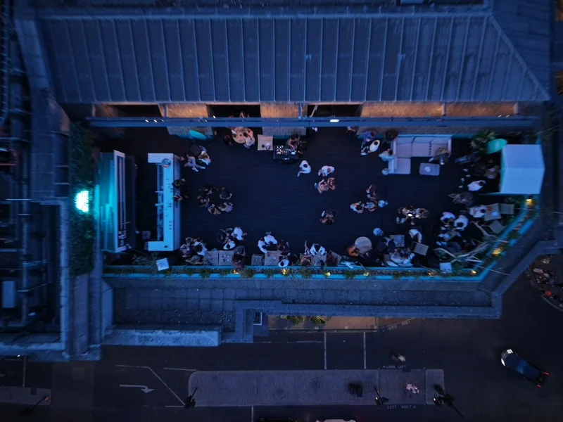 Overhead view of guests on a blue-lit rooftop terrace