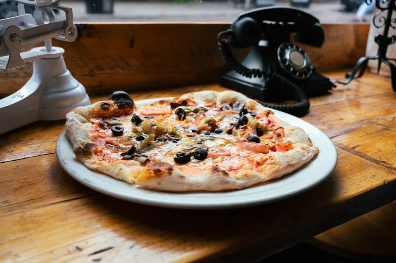 Pizza beside a vintage telephone on a wooden table