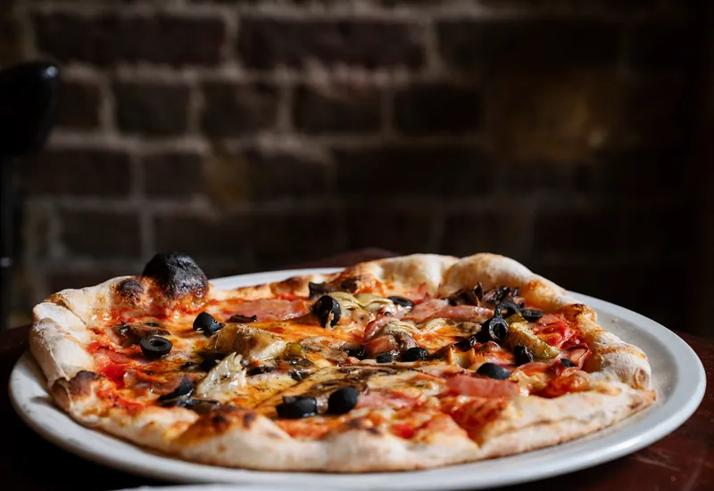 Pizza with olives against the brick wall at Bocca in Cielo