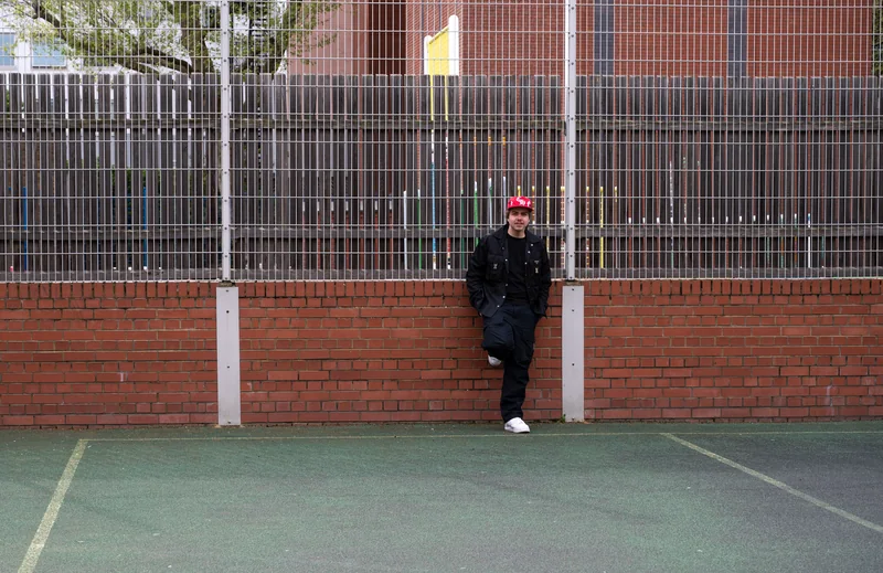 Player leaning against the fence of an outdoor basketball court