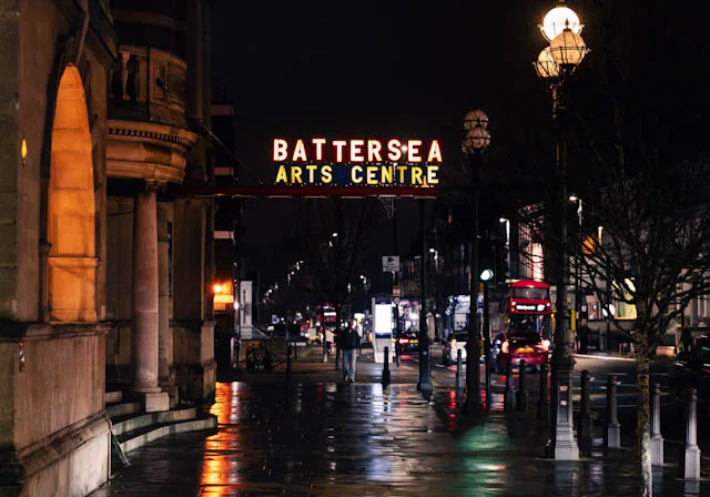 Rainy London street outside Battersea Arts Centre with red bus reflections