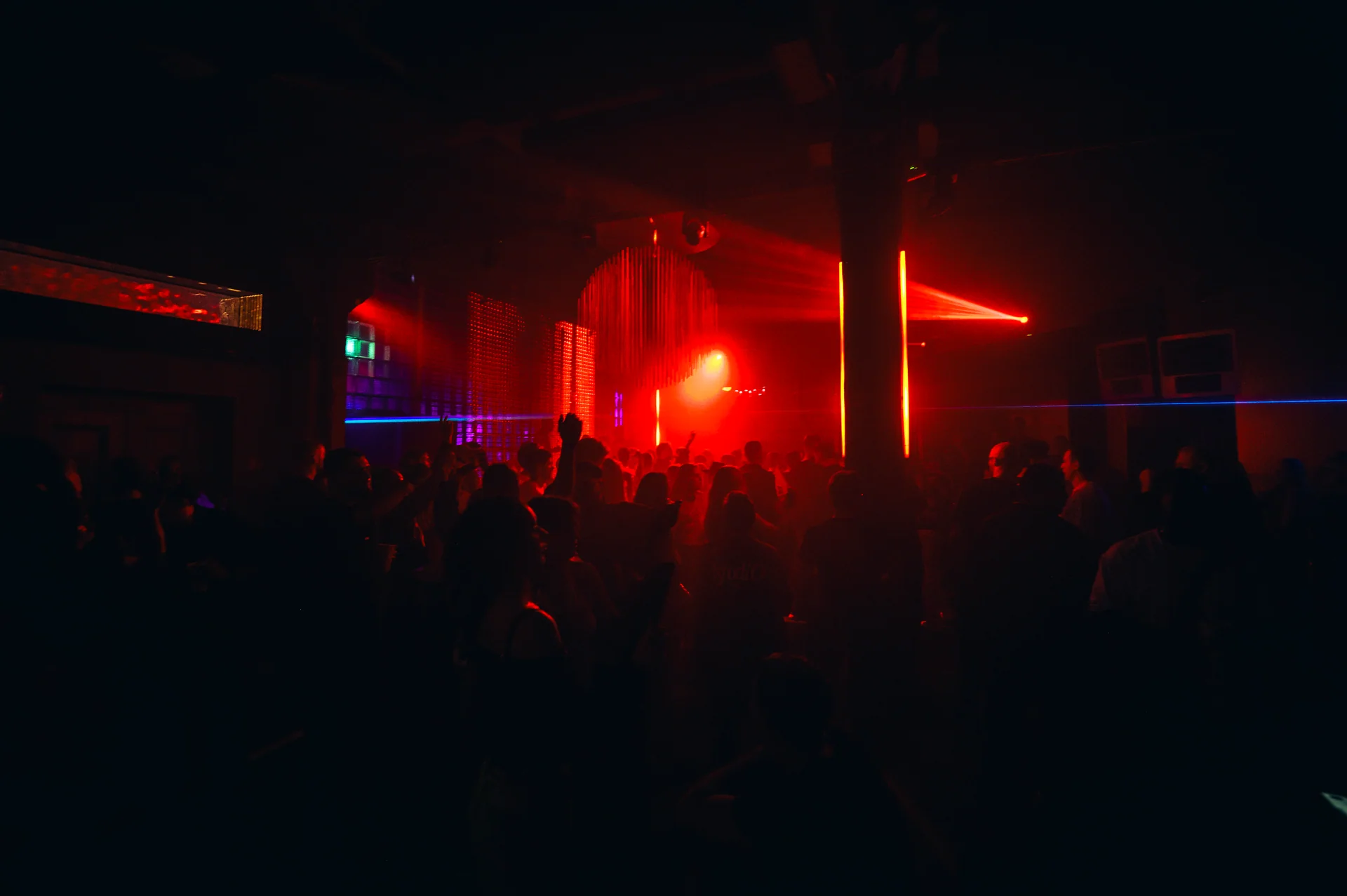 A crowd beneath red lights at the District and Gallery 1986 event