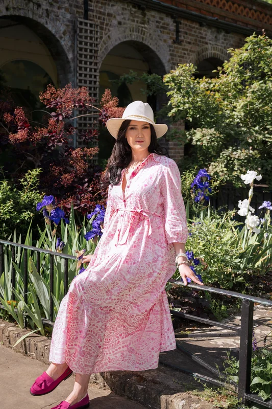 Seated garden portrait in a pink dress and white hat