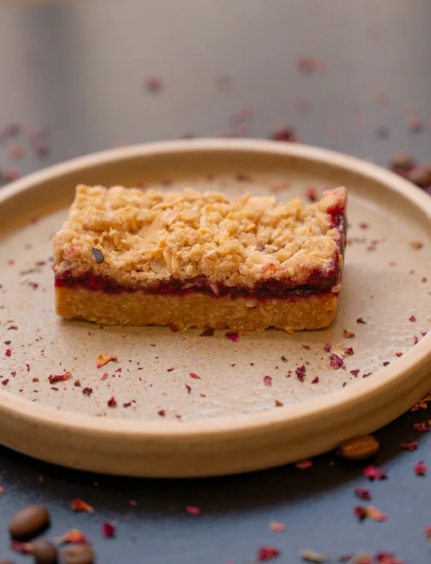 Slice of cake on a ceramic plate with scattered petals