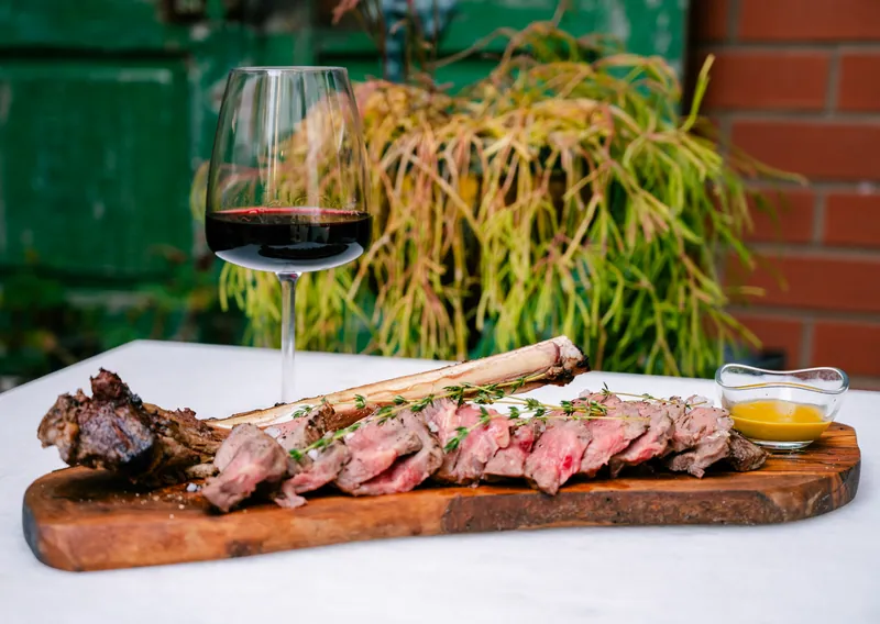 Steak and red wine against a green doorway at Mare Fabris Osteria