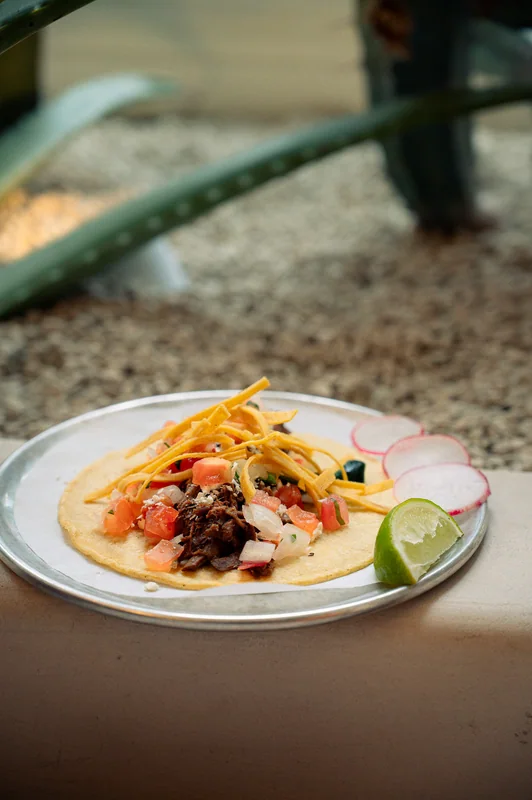 Tacos with colourful toppings and lime on a pale plate