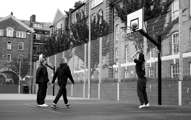 Three players beneath the hoop on an outdoor court