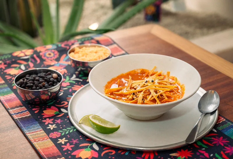 Tortilla soup with crispy strips, lime and side dishes