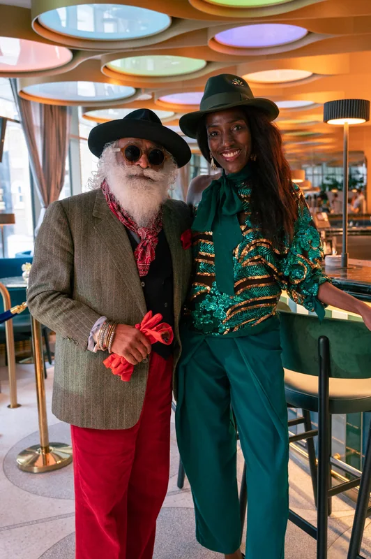 Two guests in hats posing beneath the colourful BoTree ceiling