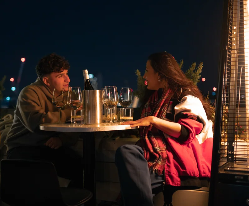Two guests talking at a rooftop table at Aqua Nueva