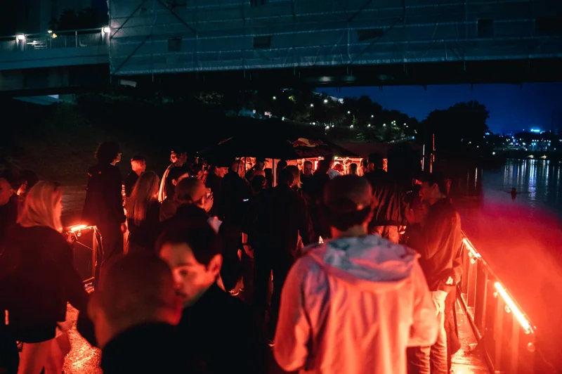 View across the riverside crowd and glowing DJ canopy