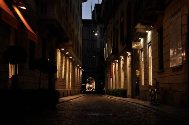 Warm street lights illuminating a narrow cobbled alley at dusk
