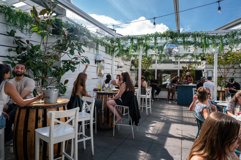 Wide view of the white rooftop venue and guests beneath blue sky at Bubba Oasis
